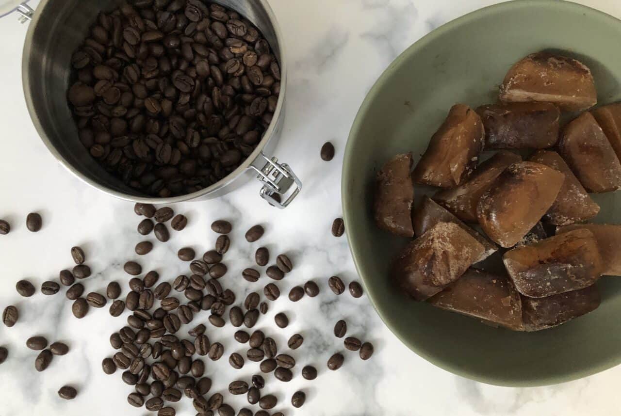 Cold coffee ice in a bowl next to beans